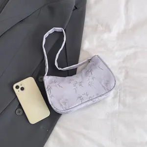 Detail of lavender crescent bag with bamboo leaf pattern and satin finish on white cloth