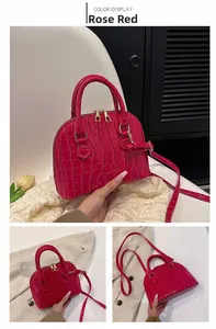 Detail of rose red crocodile pattern shell bag with golden hardware and shoulder strap