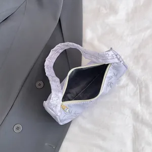 Detail view of a lavender shoulder bag with dark bamboo leaf prints on grey blazer