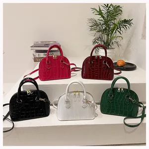 Five crocodile pattern shell bags in various colors displayed on a white tiered stand