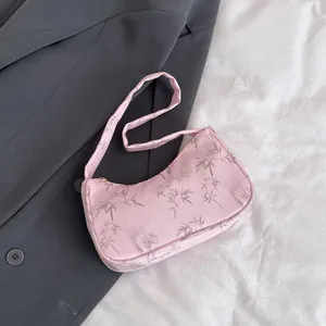 Detail of pink satin shoulder bag with bamboo leaf print on dark grey blazer
