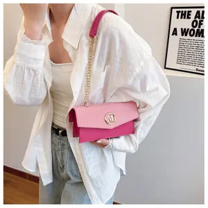 Detail of pink plaid crossbody bag with gold M logo and chain strap on a model
