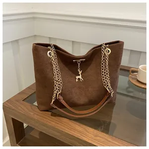 Detail of coffee brown tote with frosted texture, gold deer pendant and chain strap