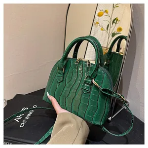 Detailed view of dark green crocodile pattern shell bag with golden hardware and strap