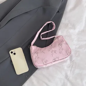 Macro shot of pink satin underarm bag with bamboo leaf pattern on dark suit fabric