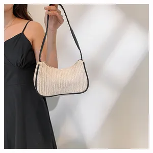 Detail of woven crescent underarm bag with black trim and sleek shoulder strap