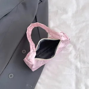 Detailed top view of pink fabric shoulder bag with leaf prints on grey suit background