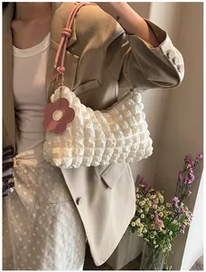 Détail du tissu à texture bulle blanche sur un sac à main avec breloque fleur rose en cuir