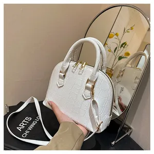 Detail shot of white crocodile embossed shell bag with gold double zipper and handle