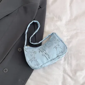 Detail view of light blue nylon underarm bag with bamboo leaf print and gold zipper