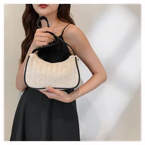 Detail of woven straw shoulder bag with black PU leather trim and zipper closure