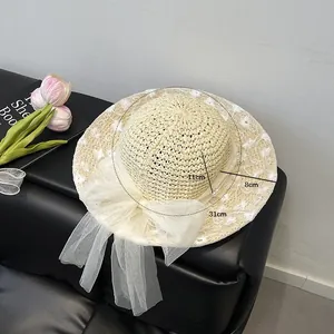 Vue détaillée du chapeau de paille avec nœud en tulle blanc et broderies montrant les mesures