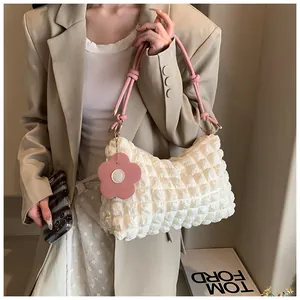 Détail du sac seau à texture gaufrée avec breloque fleur rose et bandoulière nouée