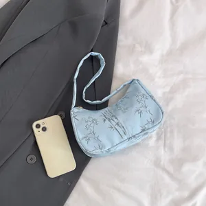 Detail of light blue hobo bag featuring dark gray bamboo leaf print on silk-like fabric