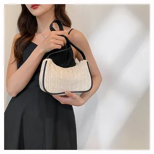 Detail of woven crescent beach bag featuring cream texture and black leather trim