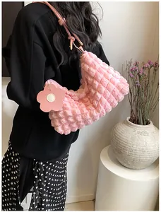 Gros plan du sac à main rose à texture bulles avec pendentif fleur et bandoulière