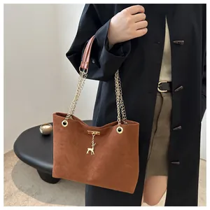 Detail of brown suede tote bag with golden chain strap and a delicate deer pendant