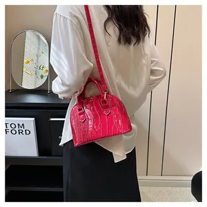 Model showing fuchsia crocodile pattern shell bag with gold hardware and shoulder strap