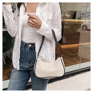 Detailed close-up of woven cream moon bag with black leather handle and V-shaped texture
