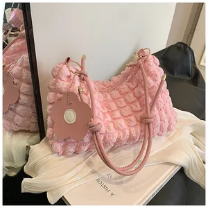 Détail du sac rose texture popcorn avec breloque fleur sur tissu en soie blanche