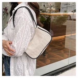 Detail of woven straw shoulder bag with black leather trim and contrasting white texture