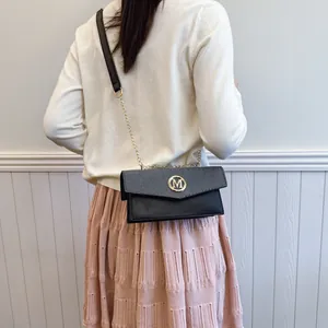 Minimalist square crossbody bag with gold M logo on black and grey leather patchwork