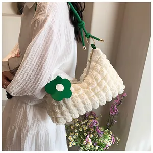 Détail de la texture gaufrée et du pendentif fleur verte sur un sac à bandoulière blanc