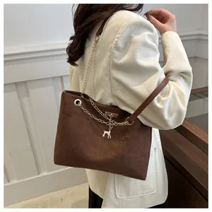 Close-up of matte dark brown suede tote bag with chain strap and small deer pendant