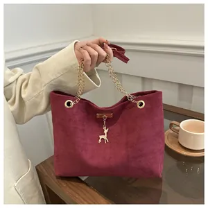 Detailed macro view of the frosted burgundy leather texture and golden deer charm