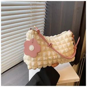 Détail du tissu à bulles blanc et poignée rose avec breloque fleur sur le sac