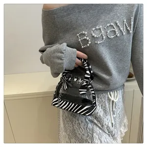 Dettaglio della borsa in PVC trasparente zebrata con catena argento indossata dal modello