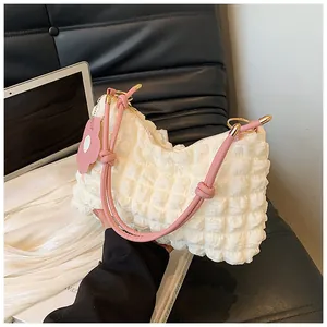 Détail du sac seau blanc gaufré avec breloque fleur rose et bandoulière à nœud