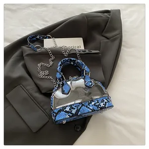Dettaglio borsa a conchiglia in PVC trasparente con finiture in pelle di serpente blu e catena