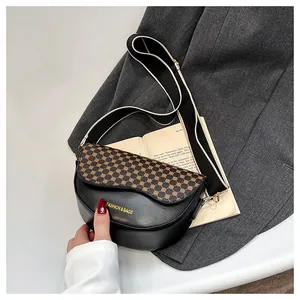 Detail of a black leather saddle bag featuring leopard print flap and wide striped strap