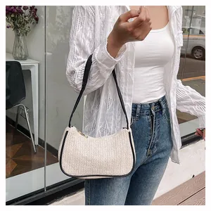 Detail of woven straw shoulder bag with beige V-pattern and black leather trim accents