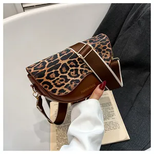 Detailed view of leopard print saddle bag with wide strap styled with a grey blazer