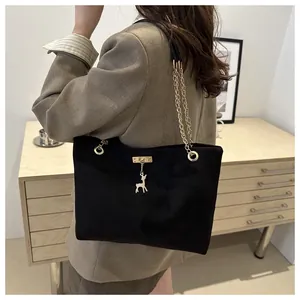 Close-up of black corduroy tote bag featuring a golden deer charm and chain strap