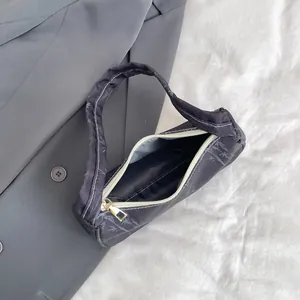 Detail of black shoulder bag showing grey leaf patterns and gold zipper puller on top