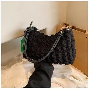 Détail du sac matelassé noir avec pendentif fleur verte et fermeture éclair métallique
