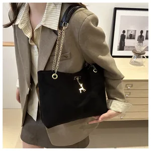 Close-up of black matte tote bag featuring gold chain strap and a decorative gold deer charm