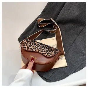 Detail of a brown saddle bag with leopard print flap and wide adjustable strap