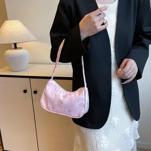 Detail of pink satin underarm bag with bamboo leaf pattern worn by a female model