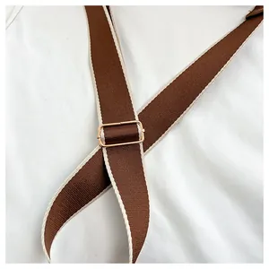 Detail of woven brown shoulder strap with gold metal buckle and cream trim finish
