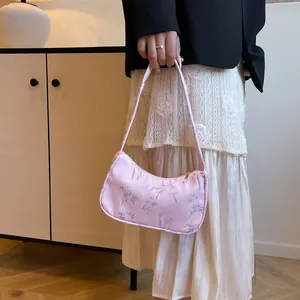 Detailed view of pink silk underarm bag with bamboo leaf print and gold zipper