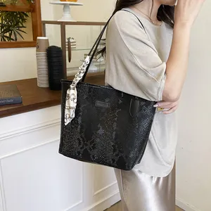 Large black snake-textured tote bag with decorative silk scarf and fashion logo