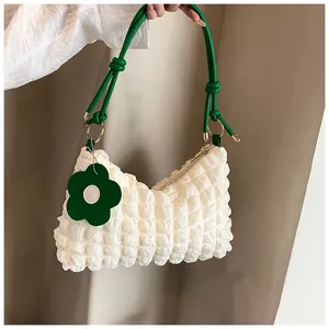 Détail du sac cylindre blanc à bulles avec poignée verte et breloque fleurie