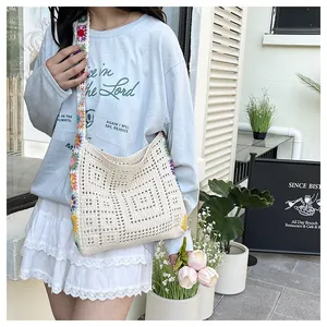 Détail d'un sac bandoulière au crochet beige avec sangle à fleurs tricotées colorées