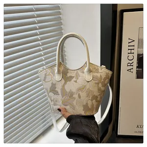 Detail of floral embroidery on cream canvas bucket bag with elegant scalloped top edge