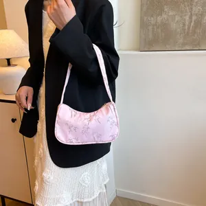 Chic pink underarm bag with silver bamboo leaf patterns worn by a model in a minimalist room