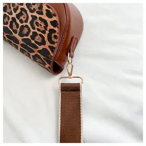 Detail of leopard print flap bag featuring gold-tone hardware and wide fabric strap
